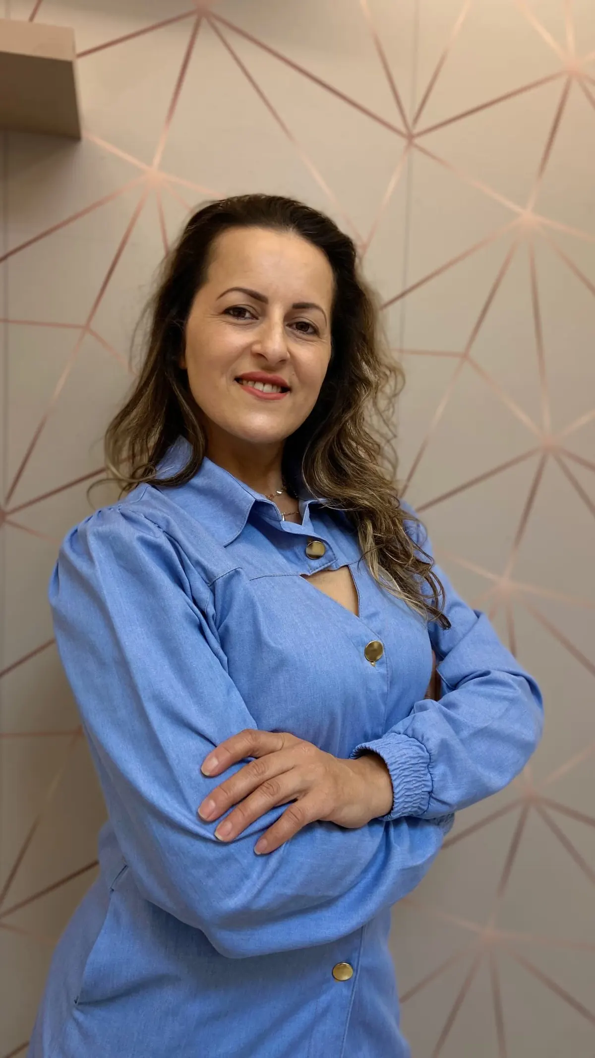 Andreia Firmino, esteticista, sorrindo de braços cruzados em seu espaço em Joinville